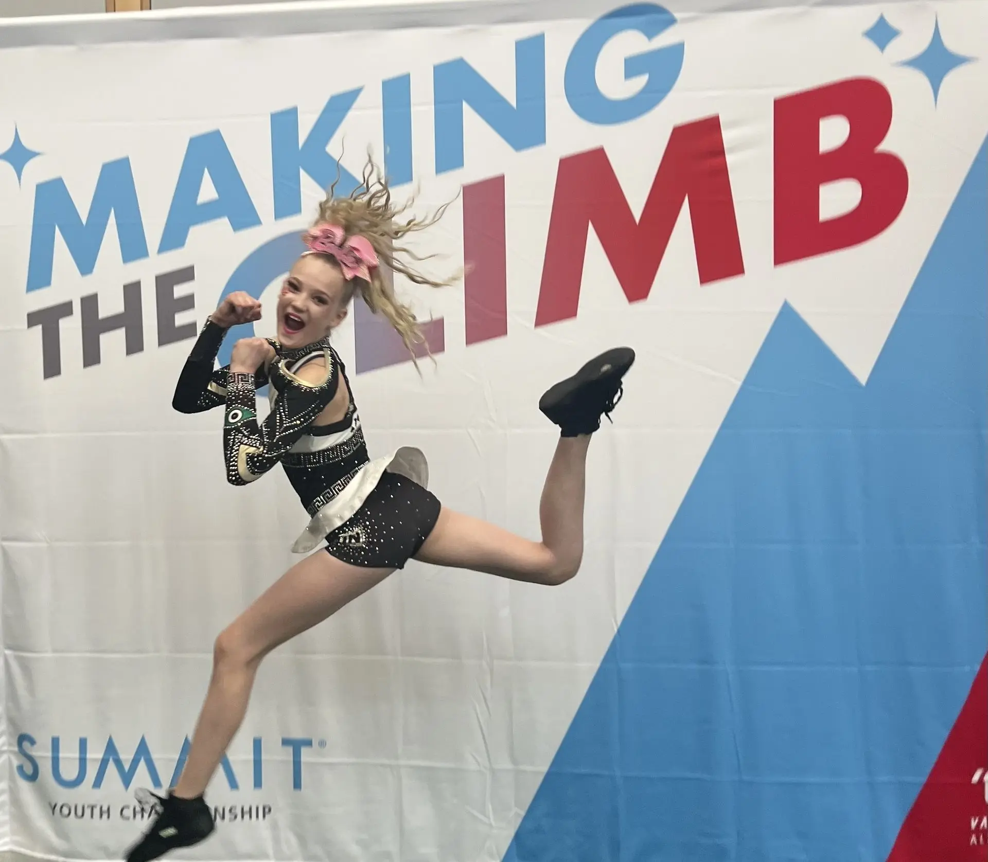 cheer athlete jumping for joy in front of a youth summit sign